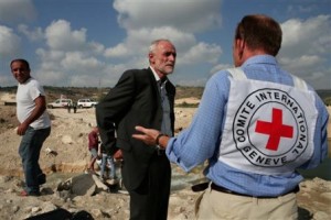 In this photo released by the International Committee of the Red Cross, ICRC President Jakob Kellenberger, center, pauses after crossing on foot from one side of the Litani River to the other following Israeli bombardment, on his way to visit the port city of Tyre, southern Lebanon, Tuesday, Aug. 8, 2006. Kellenberger visited the area, which has been cut off from the rest of the country, to assess the organisation's humanitarian efforts in southern Lebanon. (AP Photo/Marko Kokic/ICRC)
